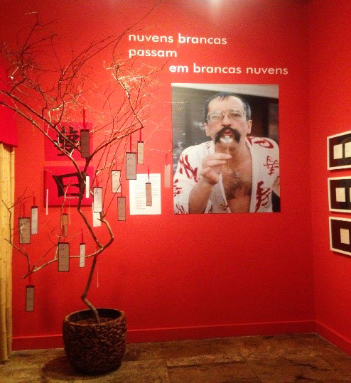 Ao lado da imagem de Paulo Leminski, Alice Ruiz recebeo público na entrada da exposição.