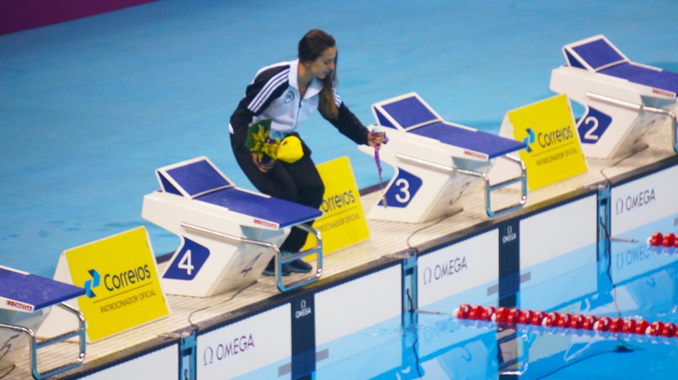 Larissa MArtins Oliveira realiza ritual comum entre nadadores. molhar a medalha na agua da piscina